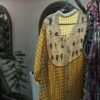 a yellow and white dress hanging on a clothes rack