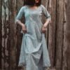 woman in blue and white dress standing beside brown wooden wall
