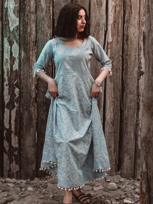 woman in blue and white dress standing beside brown wooden wall