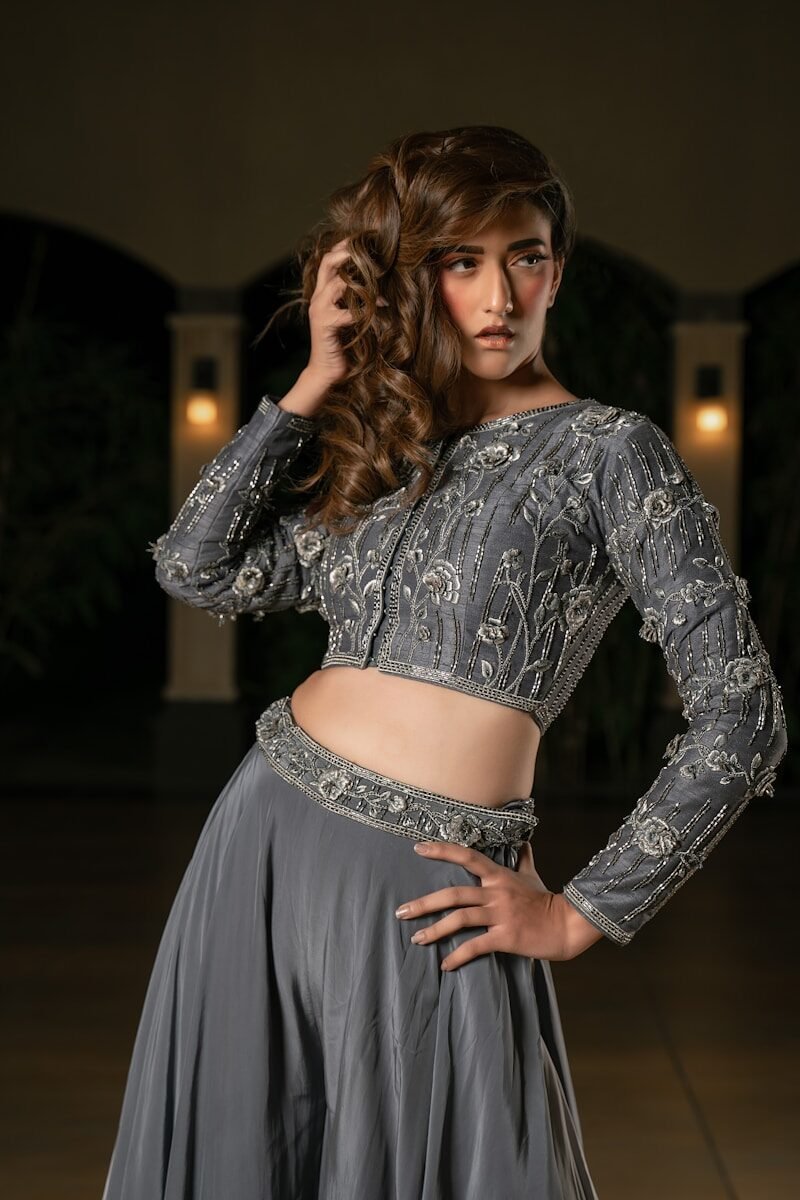 A woman in a grey embellished lehenga poses elegantly.