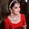 a woman wearing a red blouse and gold jewelry