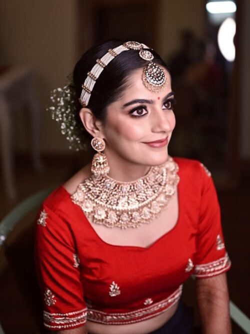 a woman wearing a red blouse and gold jewelry